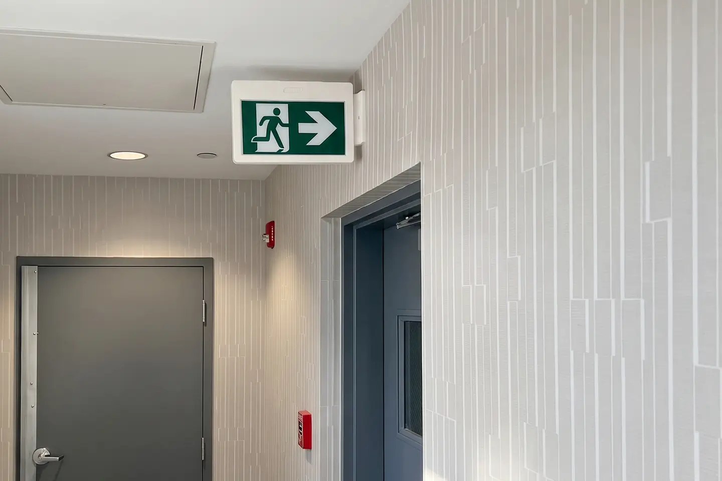 Illuminated exit sign above a doorway in a commercial corridor